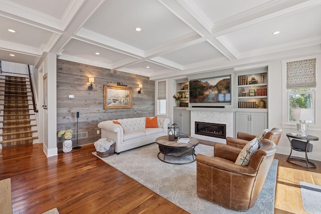 living room featuring stairs, a high end fireplace, crown molding, and wood finished floors