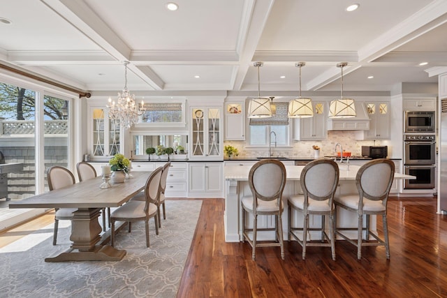 interior space featuring a wealth of natural light, custom exhaust hood, appliances with stainless steel finishes, and a sink