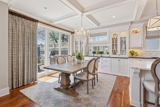 dining area with coffered ceiling, an inviting chandelier, plenty of natural light, and wood finished floors