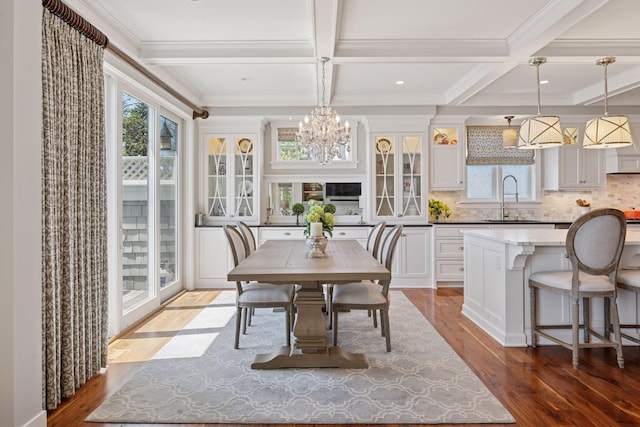 dining area featuring coffered ceiling, a notable chandelier, and wood finished floors