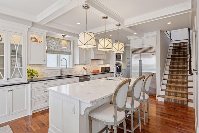 kitchen featuring built in appliances, tasteful backsplash, dark wood-style floors, and a sink