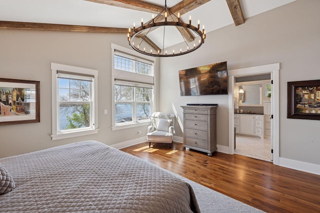 bedroom featuring wood finished floors, baseboards, beamed ceiling, ensuite bath, and a chandelier