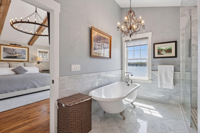 ensuite bathroom with a soaking tub, tile walls, ensuite bath, and a chandelier