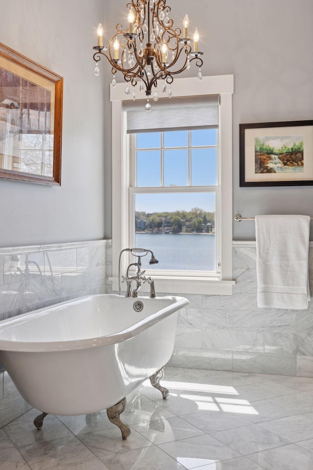 full bath featuring a chandelier, tile walls, and a freestanding tub
