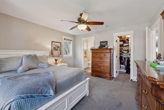 carpeted bedroom with a ceiling fan, a closet, baseboards, ensuite bathroom, and a walk in closet