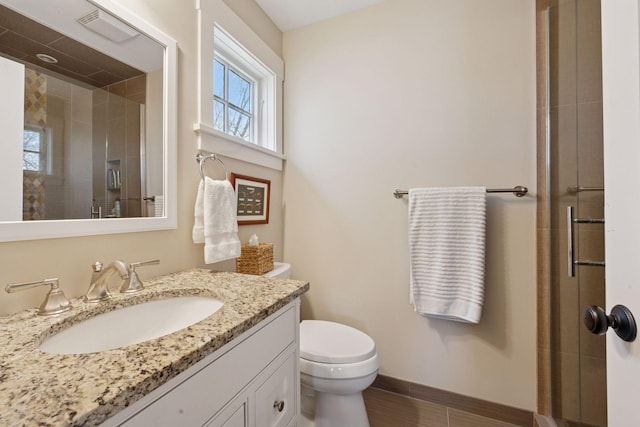 bathroom featuring a shower stall, baseboards, vanity, and toilet