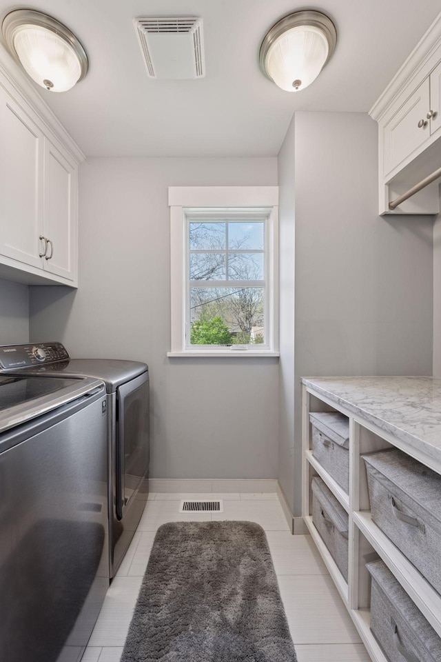 laundry room with washing machine and dryer, cabinet space, light tile patterned floors, and visible vents