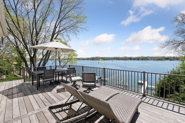 deck with a water view and outdoor dining area
