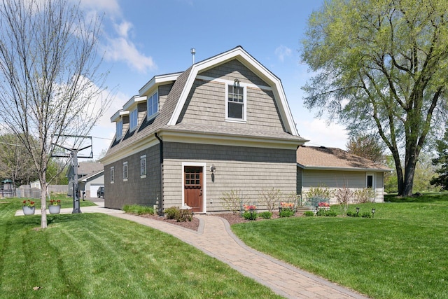 colonial inspired home with a gambrel roof, roof with shingles, and a front yard