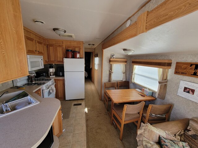 kitchen with visible vents, light countertops, a sink, and white appliances