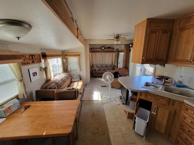 kitchen with light countertops, a sink, open floor plan, brown cabinetry, and ceiling fan