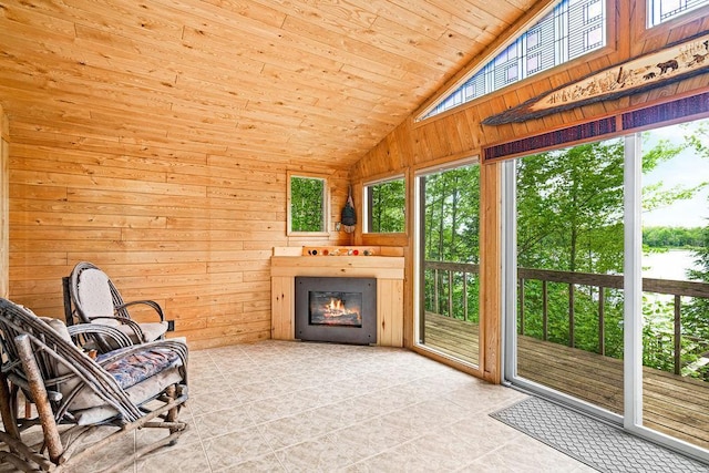 living area featuring wood ceiling, lofted ceiling, a glass covered fireplace, and wooden walls