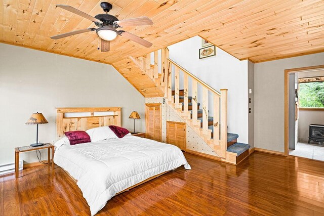 bedroom with wooden ceiling, a baseboard heating unit, vaulted ceiling, and wood finished floors