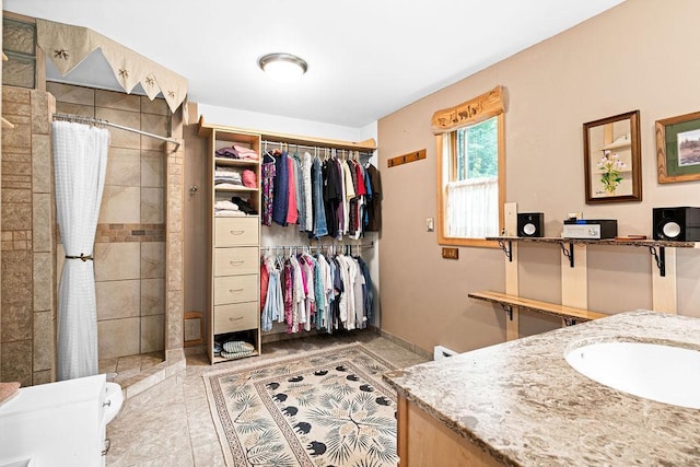 bathroom featuring vanity, tile patterned floors, a spacious closet, and tiled shower