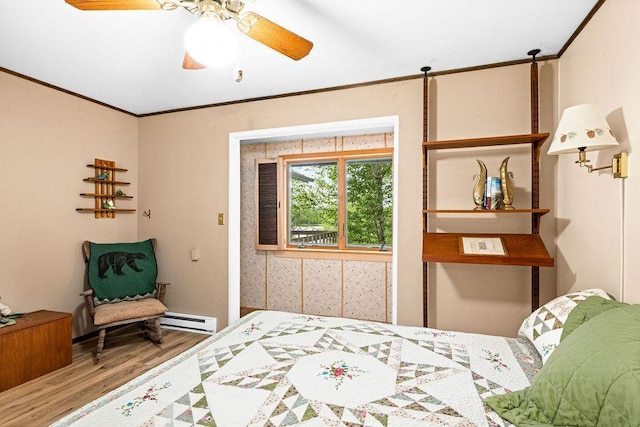 bedroom with a ceiling fan, crown molding, baseboard heating, and wood finished floors