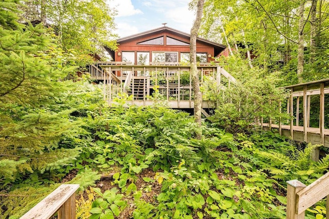 rear view of house featuring stairs and a wooden deck