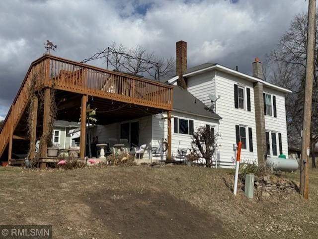 rear view of property featuring a chimney and a wooden deck