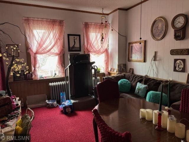 carpeted living room featuring radiator, crown molding, and wood walls
