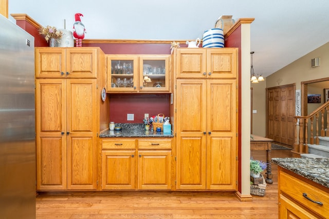 27192 237th Ave SW, Crookston Twp, MN 56716 - kitchen featuring freestanding refrigerator, light wood-style floors, glass insert cabinets, dark stone countertops, and lofted ceiling