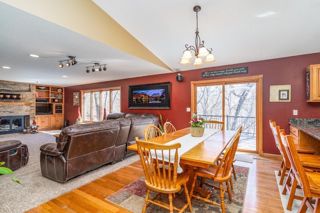 27192 237th Ave SW, Crookston Twp, MN 56716 - dining room with light wood-style flooring, a chandelier, a brick fireplace, and baseboards