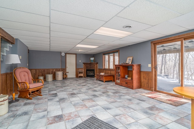 27192 237th Ave SW, Crookston Twp, MN 56716 - living area with a wainscoted wall, wooden walls, a fireplace, stone finish flooring, and a drop ceiling