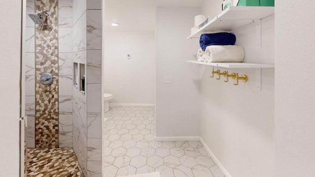 full bathroom featuring toilet, tiled shower, and baseboards