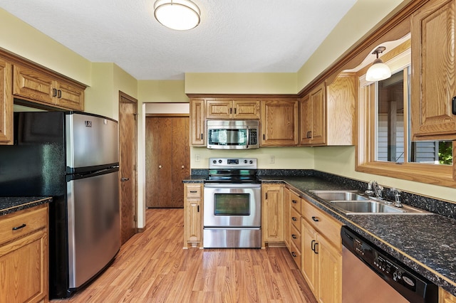 13838 Glendale Trl, Savage, MN 55378 - kitchen with appliances with stainless steel finishes, a sink, light wood finished floors, dark countertops, and a textured ceiling