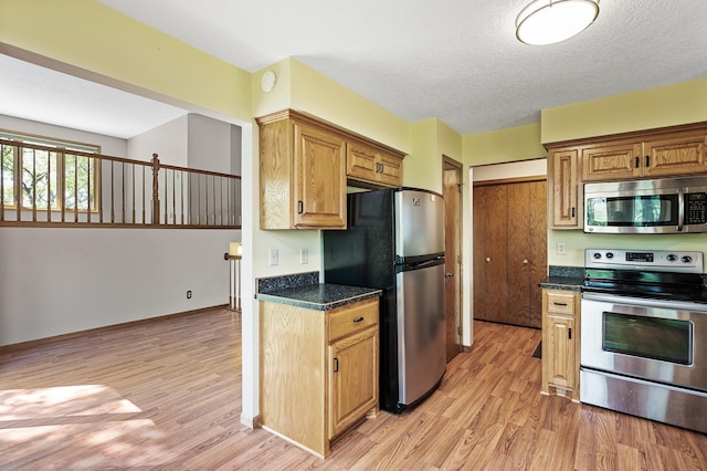 13838 Glendale Trl, Savage, MN 55378 - kitchen with appliances with stainless steel finishes, light wood-style floors, dark countertops, and a textured ceiling