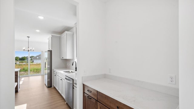 2133 Westpointe Dr, Hastings, MN 55033 - kitchen with a sink, stainless steel appliances, a chandelier, white cabinetry, and light wood-style floors