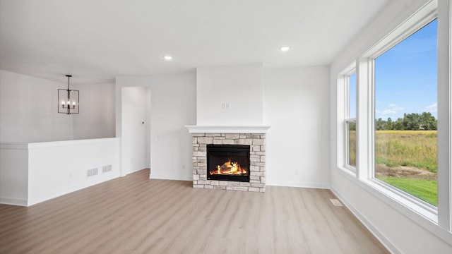 2133 Westpointe Dr, Hastings, MN 55033 - unfurnished living room with wood finished floors, a chandelier, a stone fireplace, recessed lighting, and baseboards