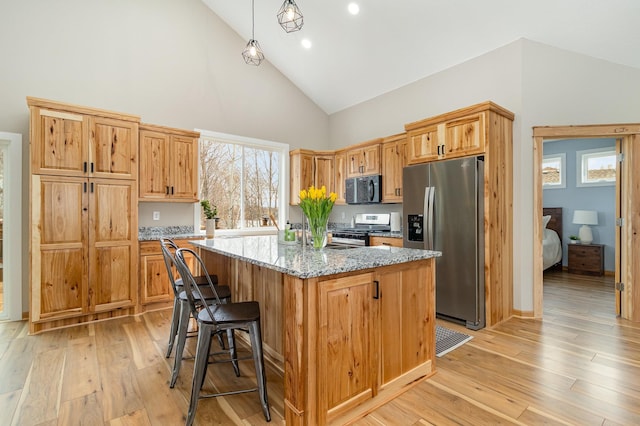 575 Elins Lake Rd SE, Cambridge, MN 55008 - kitchen with appliances with stainless steel finishes, high vaulted ceiling, a kitchen island, light wood-style floors, and light stone counters
