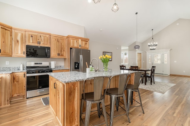 575 Elins Lake Rd SE, Cambridge, MN 55008 - kitchen featuring stainless steel appliances, light wood finished floors, a kitchen island with sink, light stone counters, and high vaulted ceiling