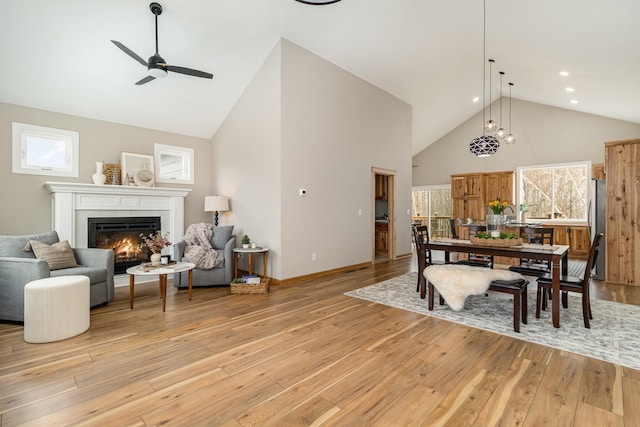 575 Elins Lake Rd SE, Cambridge, MN 55008 - dining area featuring high vaulted ceiling, light wood-type flooring, a ceiling fan, a glass covered fireplace, and plenty of natural light