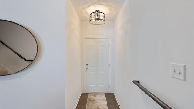 doorway featuring baseboards, wood finished floors, and a notable chandelier