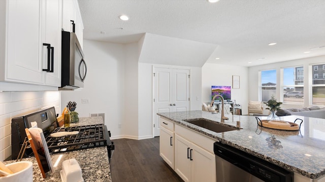 kitchen featuring dark wood-style flooring, white cabinetry, a sink, stone counters, and stainless steel appliances