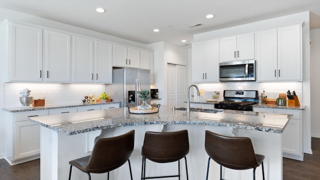 kitchen featuring appliances with stainless steel finishes, a sink, visible vents, and dark wood finished floors
