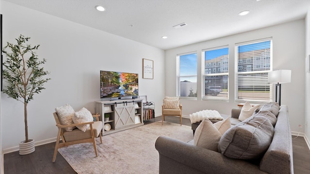 living area featuring baseboards, visible vents, and wood finished floors