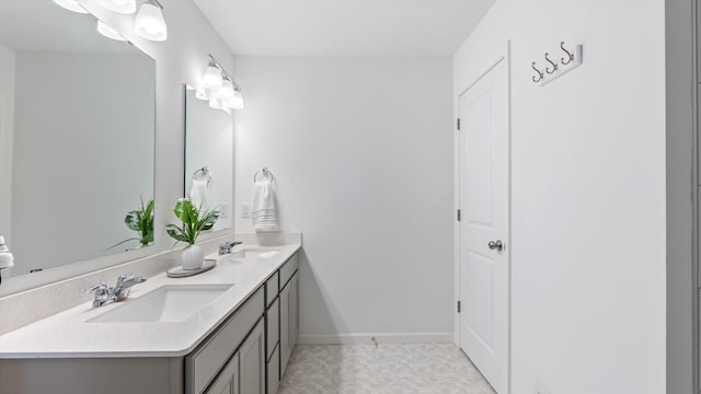 bathroom with double vanity, a sink, baseboards, and tile patterned floors