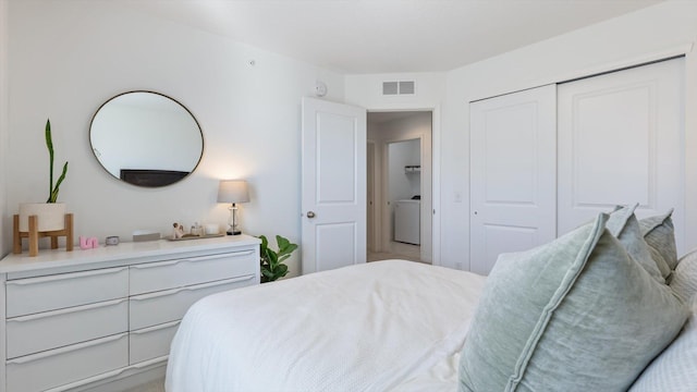 bedroom with a closet, washer / clothes dryer, and visible vents