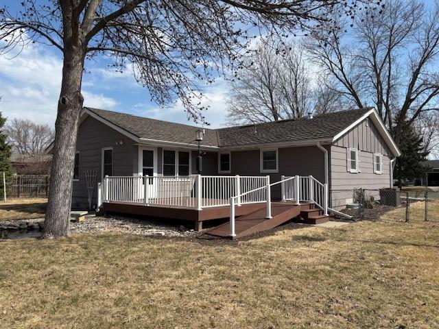 back of house with a yard, a wooden deck, fence, and board and batten siding