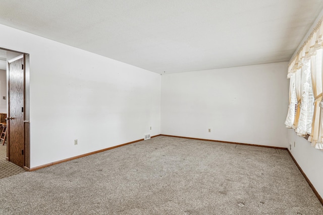 empty room with carpet flooring, baseboards, and visible vents