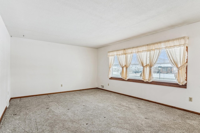 carpeted empty room with baseboards and a textured ceiling