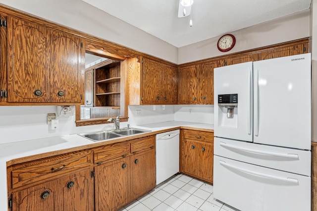 kitchen featuring brown cabinets, a sink, and white appliances