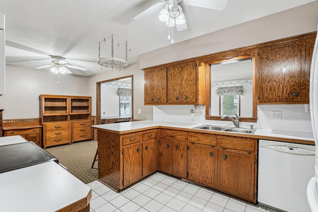 kitchen with white dishwasher, a sink, ceiling fan, a peninsula, and brown cabinets
