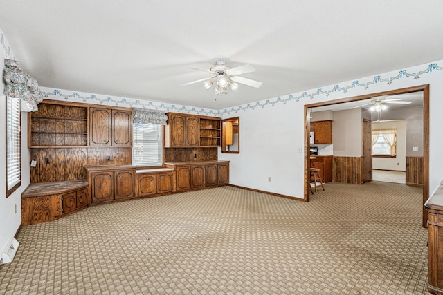 interior space featuring a ceiling fan, light colored carpet, baseboards, and open shelves