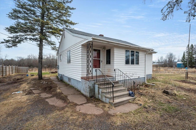 bungalow-style house featuring fence and a chimney