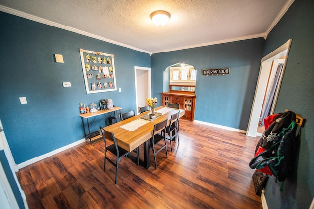 dining room featuring wood finished floors, a textured ceiling, crown molding, and baseboards