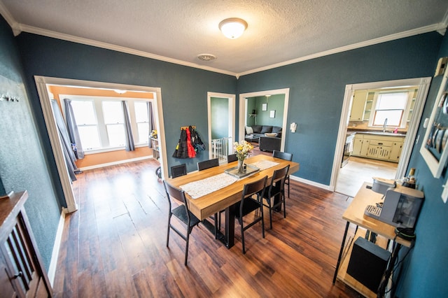 dining space featuring hardwood / wood-style floors, visible vents, crown molding, baseboards, and a textured ceiling