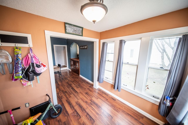 interior space with wood finished floors, a textured ceiling, and baseboards