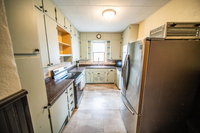 kitchen with open shelves, stainless steel appliances, a sink, and cream cabinetry